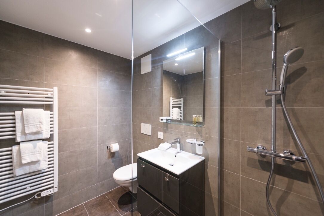 A modern bathroom with a toilet, sink, and shower.