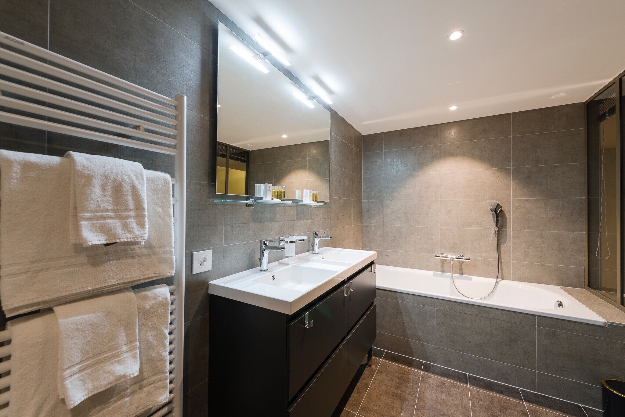 A modern bathroom with a double sink vanity, a large mirror, and a walk-in shower.