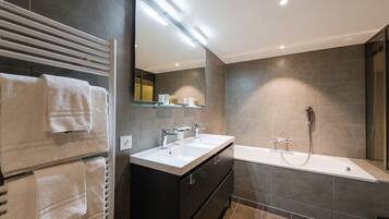 A modern bathroom with a double sink vanity, a large mirror, and a walk-in shower.