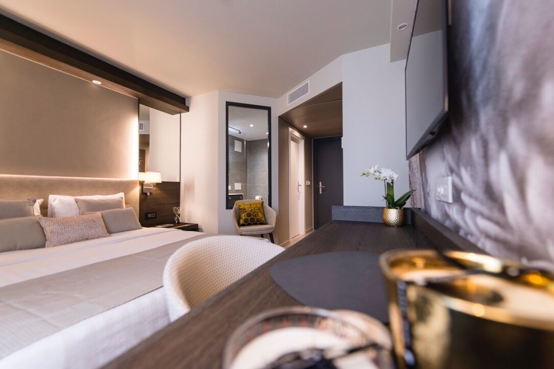 Una habitación de hotel moderna con una cama grande, un escritorio, una silla y un televisor.
