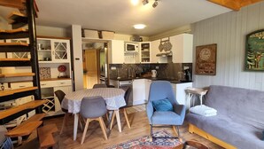 En hyggelig stue med en grå sofa, en blå lænestol og et spisebord med bordduge med mønster.