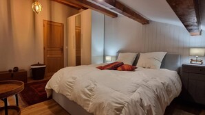 Et soveværelse med en stor seng, et natbord, en lampe, en stol og et klædeskab.