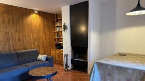 Ein gemütliches Wohnzimmer mit Sofa, rundem Couchtisch, Kamin und Bücherregal.