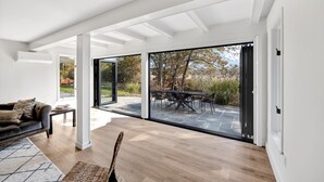 A spacious living area with a large sliding glass door leading to an outdoor patio. - Modern 6 BR,5 B MarshViews,Hot tub,5mins to beach,Chef’s Kitchen, Large Groups (Barnstable)