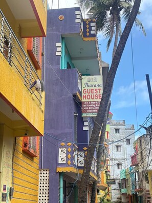 A multi-story building with a sign for 'Tharana Guest House' advertising self-cooking rooms. - JHARANA guest house (Puri)