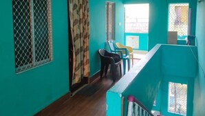 A teal-colored room with a staircase, wooden flooring, and a view of the outside. - JHARANA guest house (Puri)