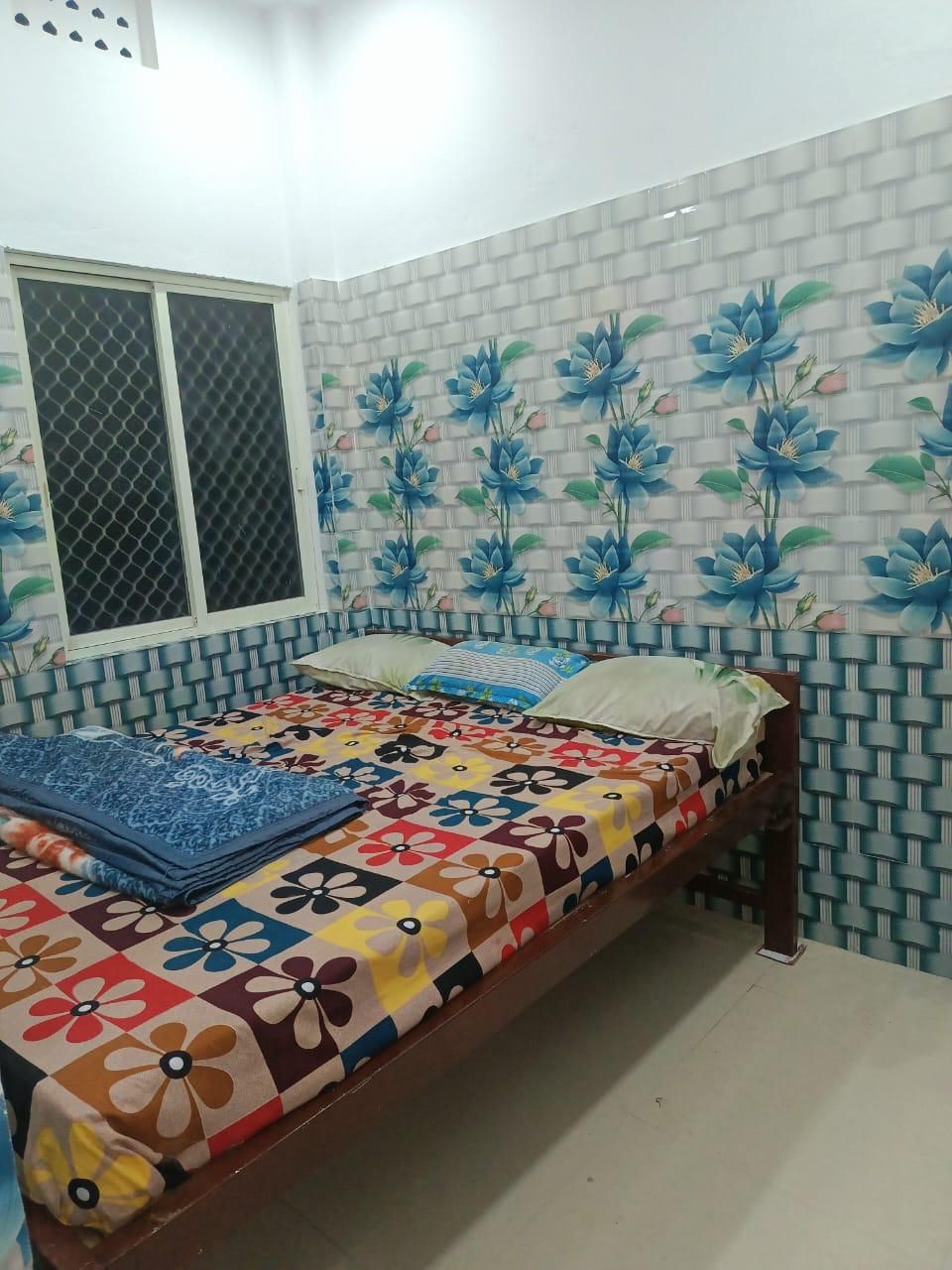 A bedroom with a bed, a window, and a wall with a floral pattern.