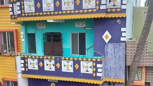 A multi-story building with a vibrant exterior featuring geometric patterns and a mix of colors. - JHARANA guest house (Puri)