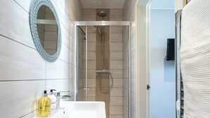 Un bany amb un lavabo blanc, un mirall i una zona de dutxa.