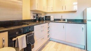A modern kitchen with white cabinets, a black countertop, a built-in oven, a microwave, and a sink. - Cozy 2bedroom Sheffield City Apartment (Sheffield)