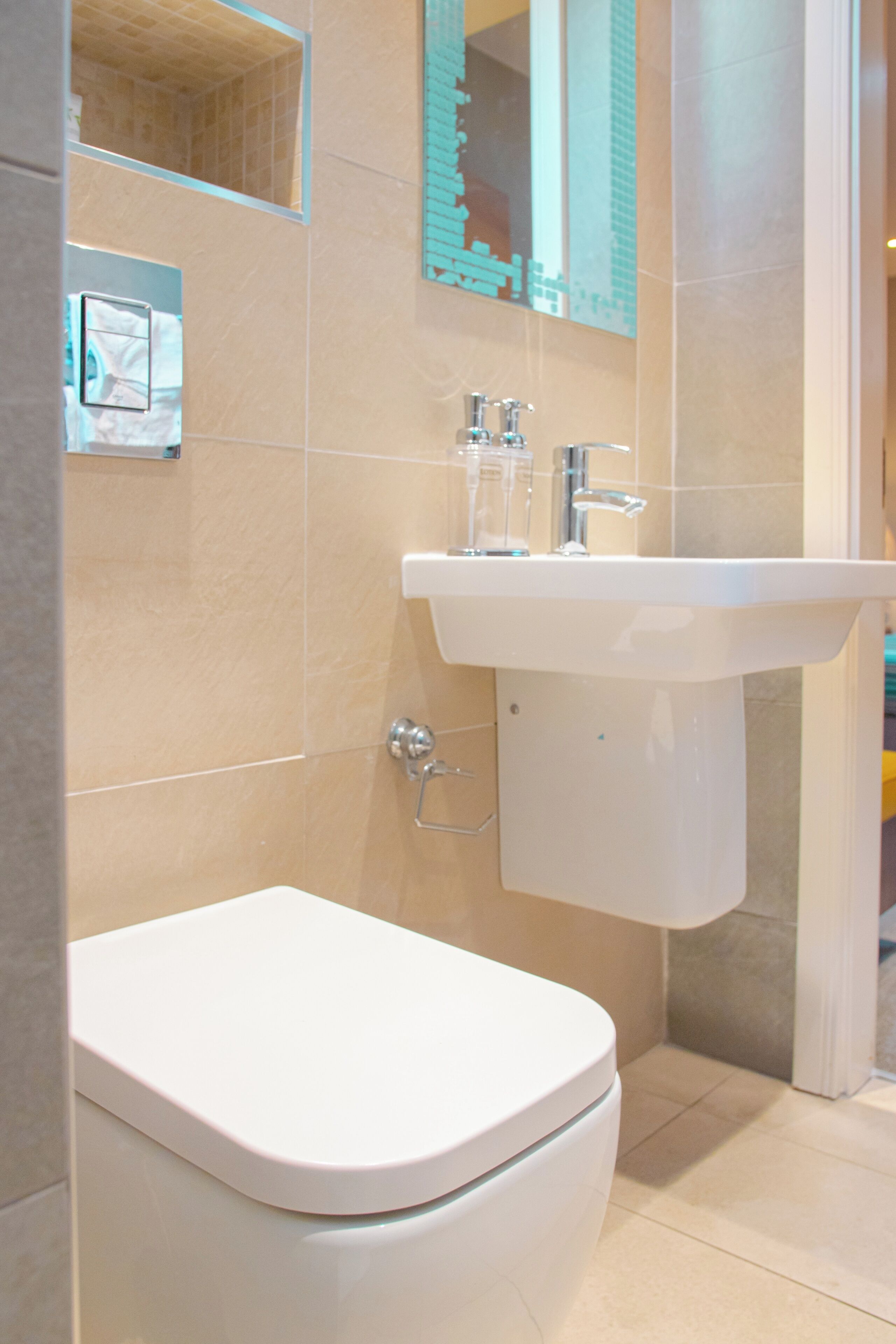 Un baño con inodoro blanco, lavabo y espejo.