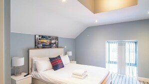 Ein modernes Schlafzimmer mit Bett, Nachttischen, einem Kopfteil, einem Wandbild und einem Fenster mit Vorhängen.