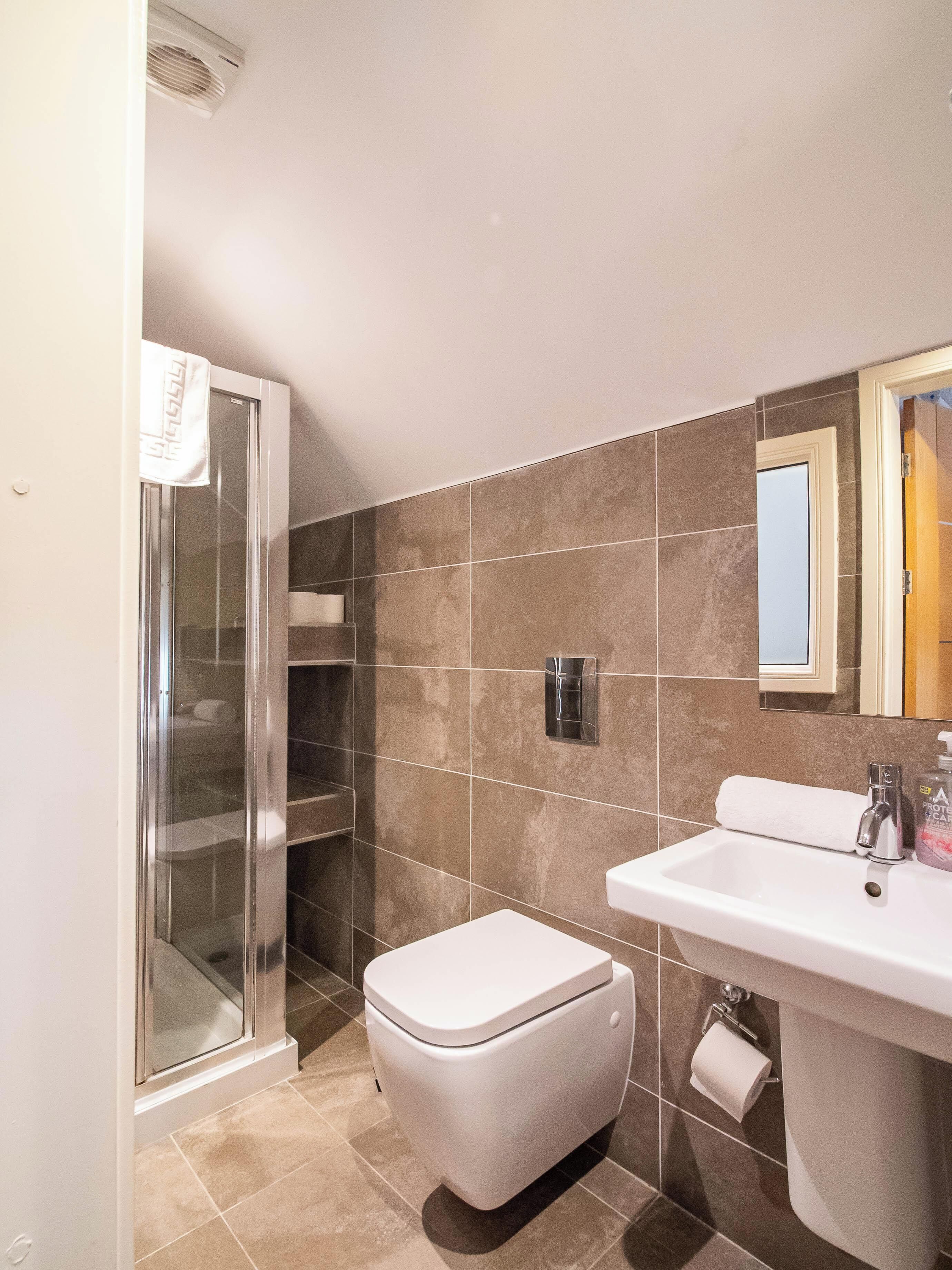 A modern bathroom with a glass shower enclosure, a toilet, a sink with a mirror, and a towel rack.