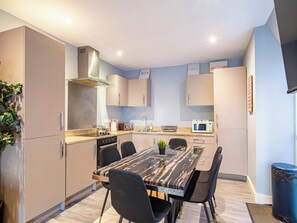A modern kitchen with a marble countertop, black chairs, and a built-in oven.