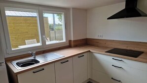 Een keuken met een raam, een spoelbak en een zwarte afzuigkap.