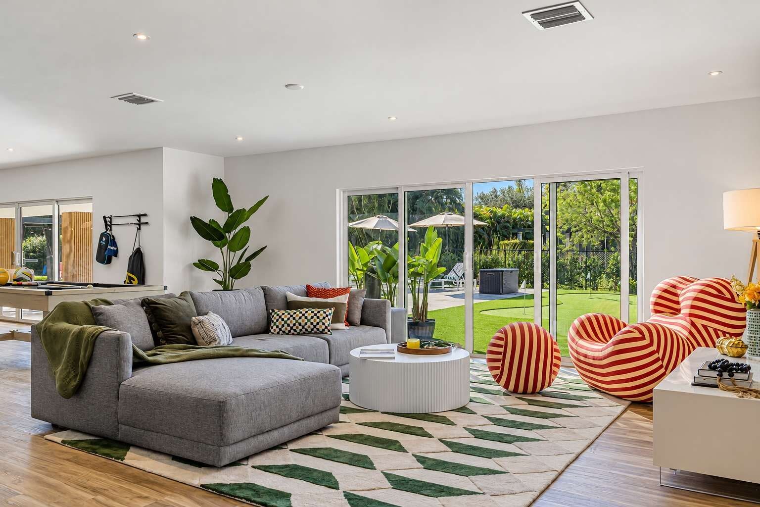 A modern living room with a grey sofa, a round coffee table, and striped armchairs.