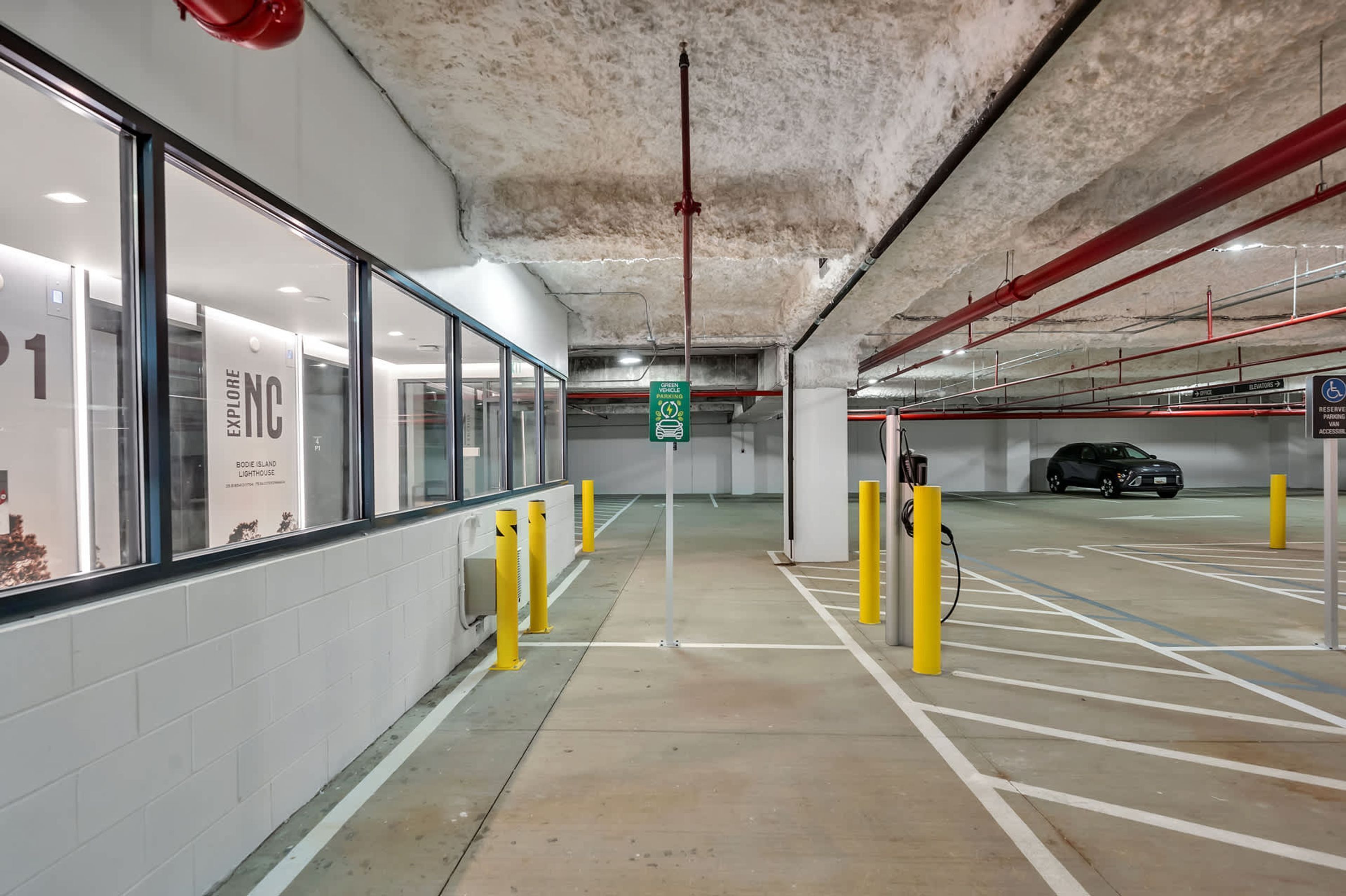 A parking garage with clear signage, including a green sign for a disabled parking space.