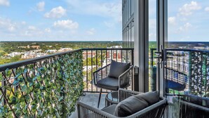 Een balkon met uitzicht op een stadsgezicht, een stoel en een rieten bank.
