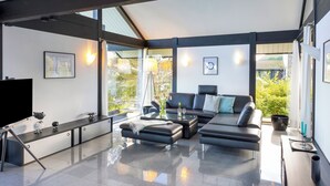 A modern living room with a large sectional sofa, a coffee table, and a flat-screen TV. - Villa Leonardo (Gebhardshain)