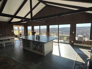 A spacious kitchen with a large island, wooden beams, and large windows offering a view of the countryside. - Charming 4 bdrm house with Views, 200 acres, Private Schools, Skiing, Hiking… (Leyden)