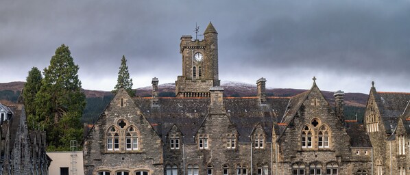 A historic stone building with multiple towers and arched windows, likely a castle or manor house.