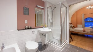 Un baño moderno con cabina de ducha de vidrio, un lavamanos blanco y un inodoro.