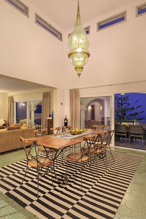 A dining area with a large table, chairs, and a patterned rug.