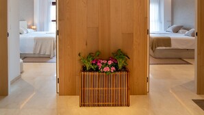 A hotel room with a wooden partition, a bed, a bedside table, and a potted plant with flowers. - Design Apartment with swimming pool Ciudad de Ciencias (València)