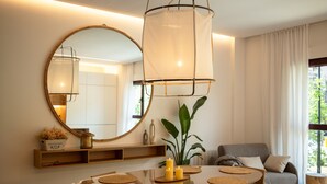 A dining area with a round table, chairs, a large mirror, and a hanging light fixture. - Design Apartment with swimming pool Ciudad de Ciencias (València)