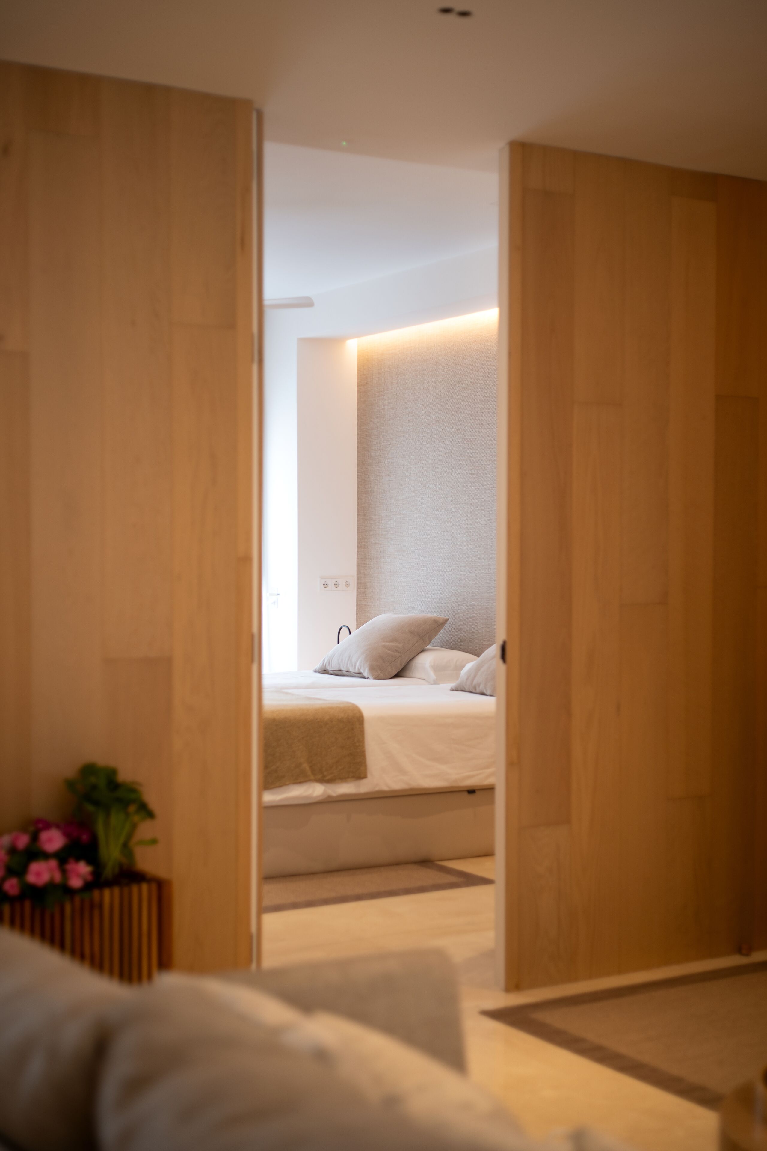 Een moderne slaapkamer met een bed, een houten garderobe en een kamerplantje.