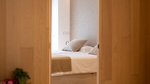 A modern bedroom with a bed, wooden wardrobe, and a bedside plant. - Design Apartment with swimming pool Ciudad de Ciencias (València)