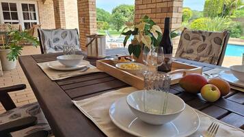 Enjoy al fresco dining with a view of the pool from this outdoor dining area, featuring a beautifully set table with fine china and a refreshing centerpiece.