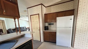 Una cocina compacta con armarios de madera, un refrigerador blanco y un lavavajillas.
