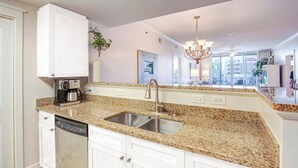 Una cocina moderna con encimeras de granito, electrodomésticos de acero inoxidable y armarios blancos.