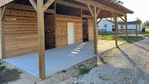 Eine Holzhütte mit überdachter Veranda und einer Tür, vermutlich ein Stall oder eine Scheune.