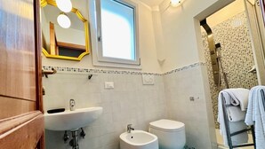A bathroom with a sink, two toilets, a bidet, a mirror, and a shower area. - Terrace Studio   Apartment with panoramic terrace (Florence)