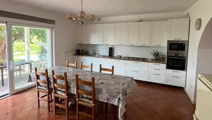 A spacious kitchen with white cabinets, a dining table with chairs, and a sliding glass door leading to an outdoor area.