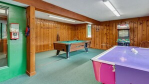 Ein Billardtisch in einem Raum mit Holzwänden und einer grünen Tür.