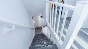 Un escalier avec des rampes blanches et une moquette à motifs.