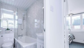 A modern bathroom with a shower, toilet, and sink.
