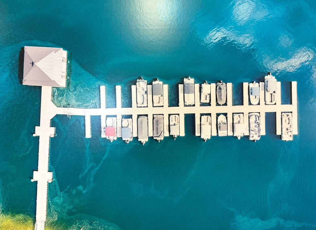 Vista aérea de un puerto deportivo con hileras de barcos amarrados y una estructura de muelle blanco.
