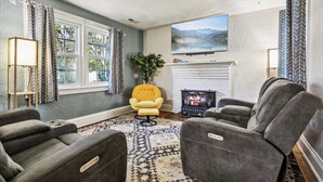 A living room with a fireplace, comfortable seating, a large window, and a flat-screen TV. - Family and dog friendly home, 30+ day stays (Norfolk)