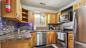 A modern kitchen with wooden cabinets, stainless steel appliances, a microwave, and a dishwasher. - Family and dog friendly home, 30+ day stays (Norfolk)