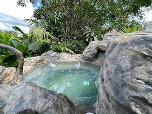 A hot spring surrounded by natural rock formations and lush greenery.
