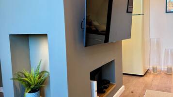 A modern living room with a built-in TV, a small plant, and a white refrigerator.