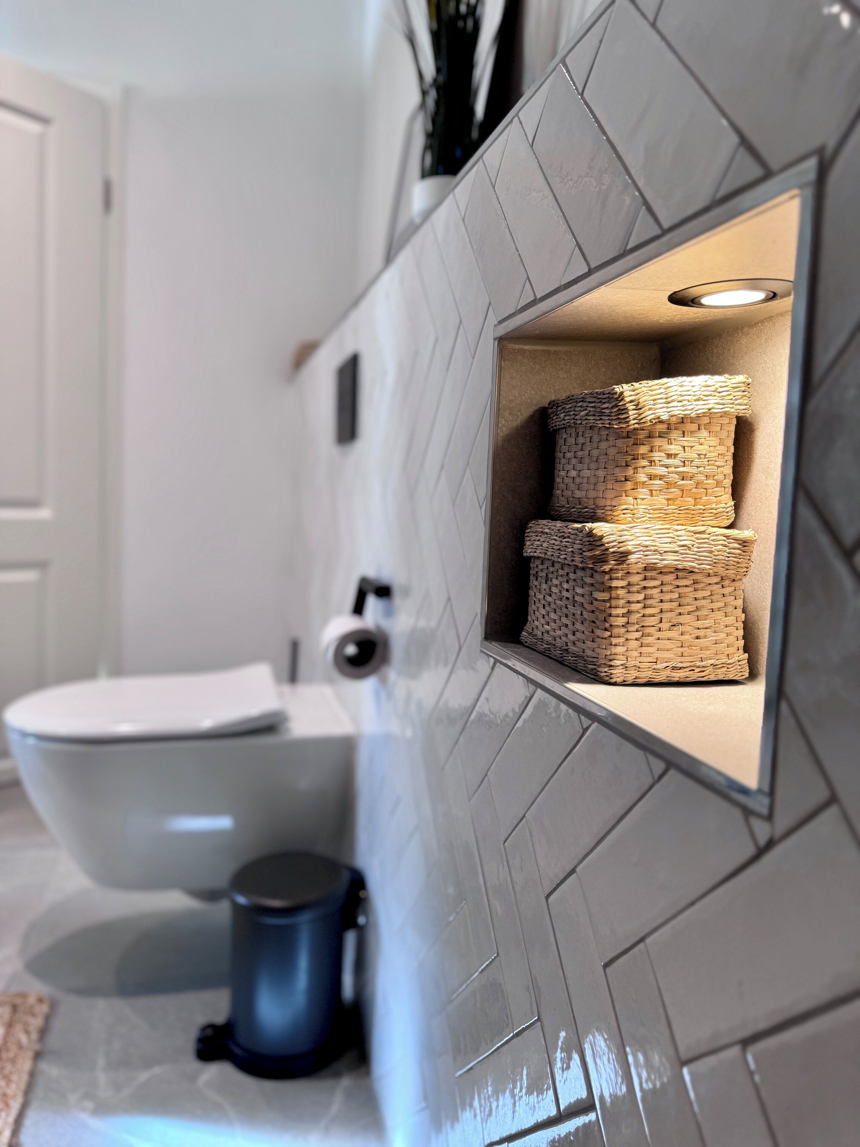 Ein Badezimmer mit Toilette, Mülleimer und Waschbecken mit modernem Design.
