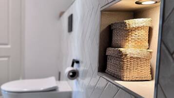 Ein Badezimmer mit Toilette, Mülleimer und Waschbecken mit modernem Design.