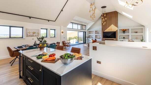A spacious kitchen with a large island, modern pendant lights, and a view of the outdoors. - 4 Bed in Instow (oc-d30010) (Instow)