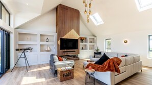 A modern living room with a high ceiling, a telescope, and a large TV. - 4 Bed in Instow (oc-d30010) (Instow)