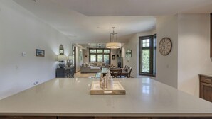 Una cocina amplia con una isla grande, un comedor con mesa y sillas, y una sala de estar con sofá y chimenea.